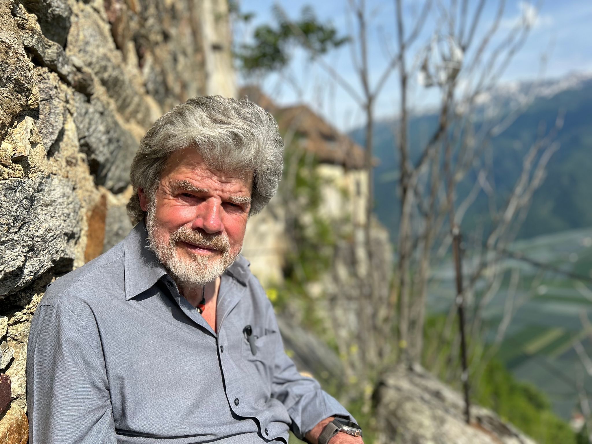 Der Bergsteiger Reinhold Messner sitzt an seinem Schloss Juval auf einer Bank. Foto: Christoph Sator/dpa