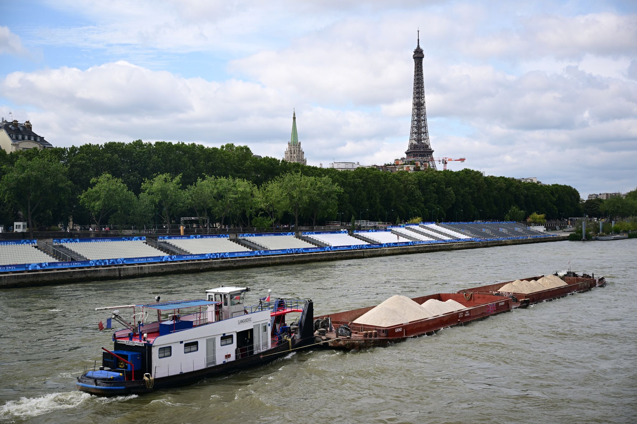 Keine Filmszene, sondern ein Foto aus dem Sommer während Olympia. Ein Schiff passiert Tribünen, im Hintergrund ist der Eiffelturm zu sehen. Im Netflix-Hit «Im Wasser der Seine» treibt dagegen ein Hai sein Unwesen im Pariser Gewässer. (Archivbild) Foto: Sina Schuldt/dpa